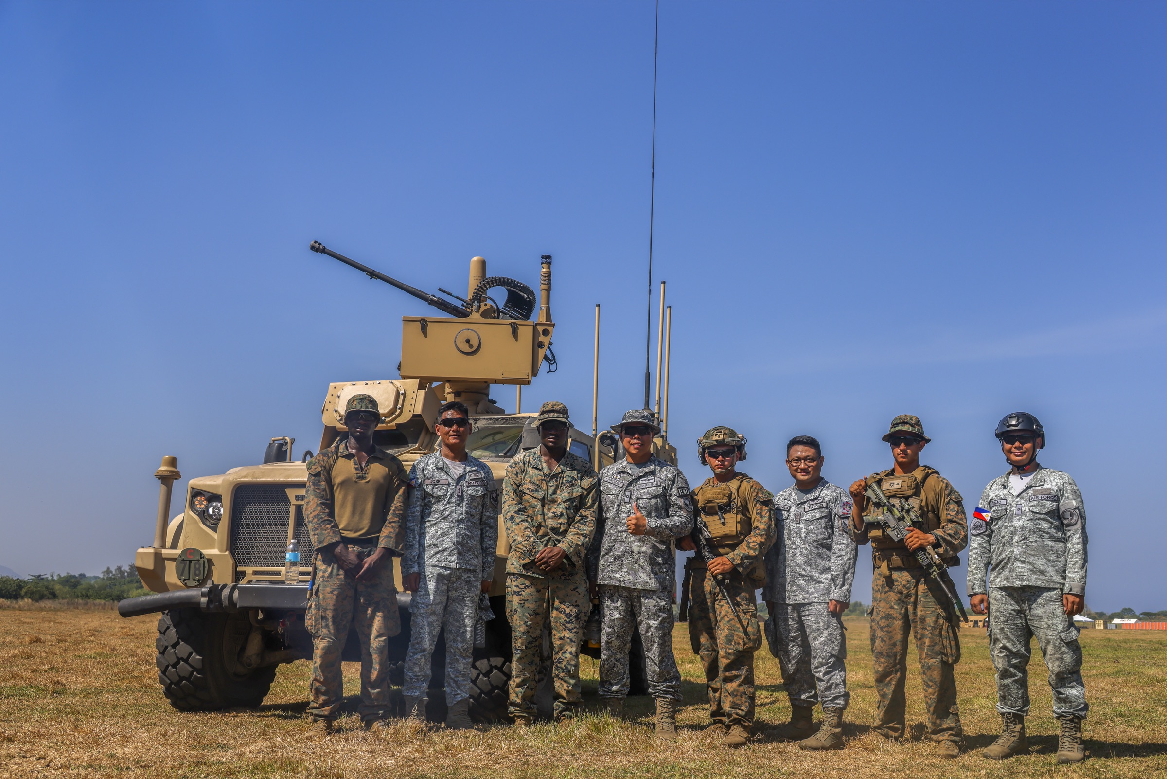 U.S. service members from multiple branches standing in front of a tactical vehicle.